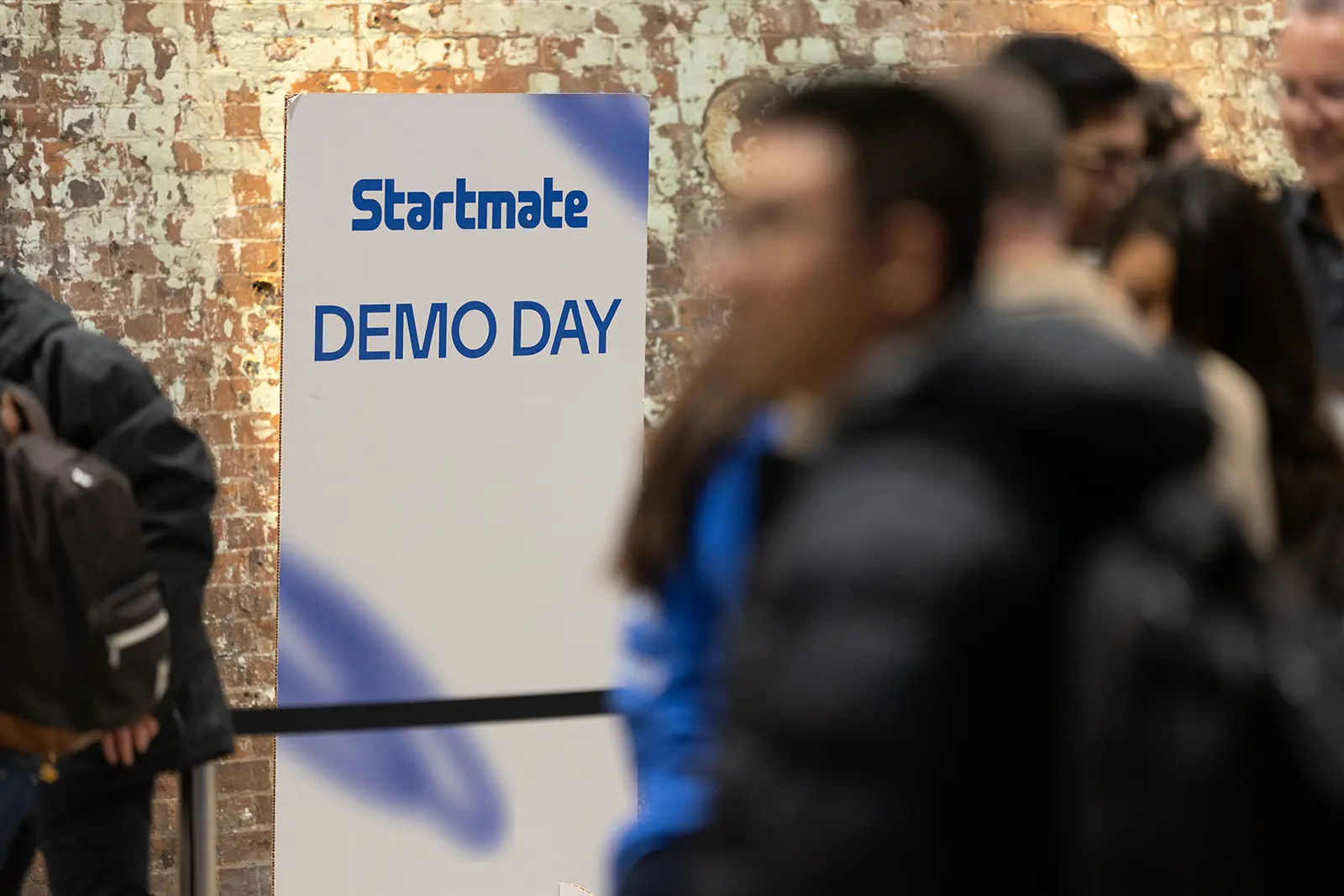 Startmate Demo Day sign with crowd gathering in the background